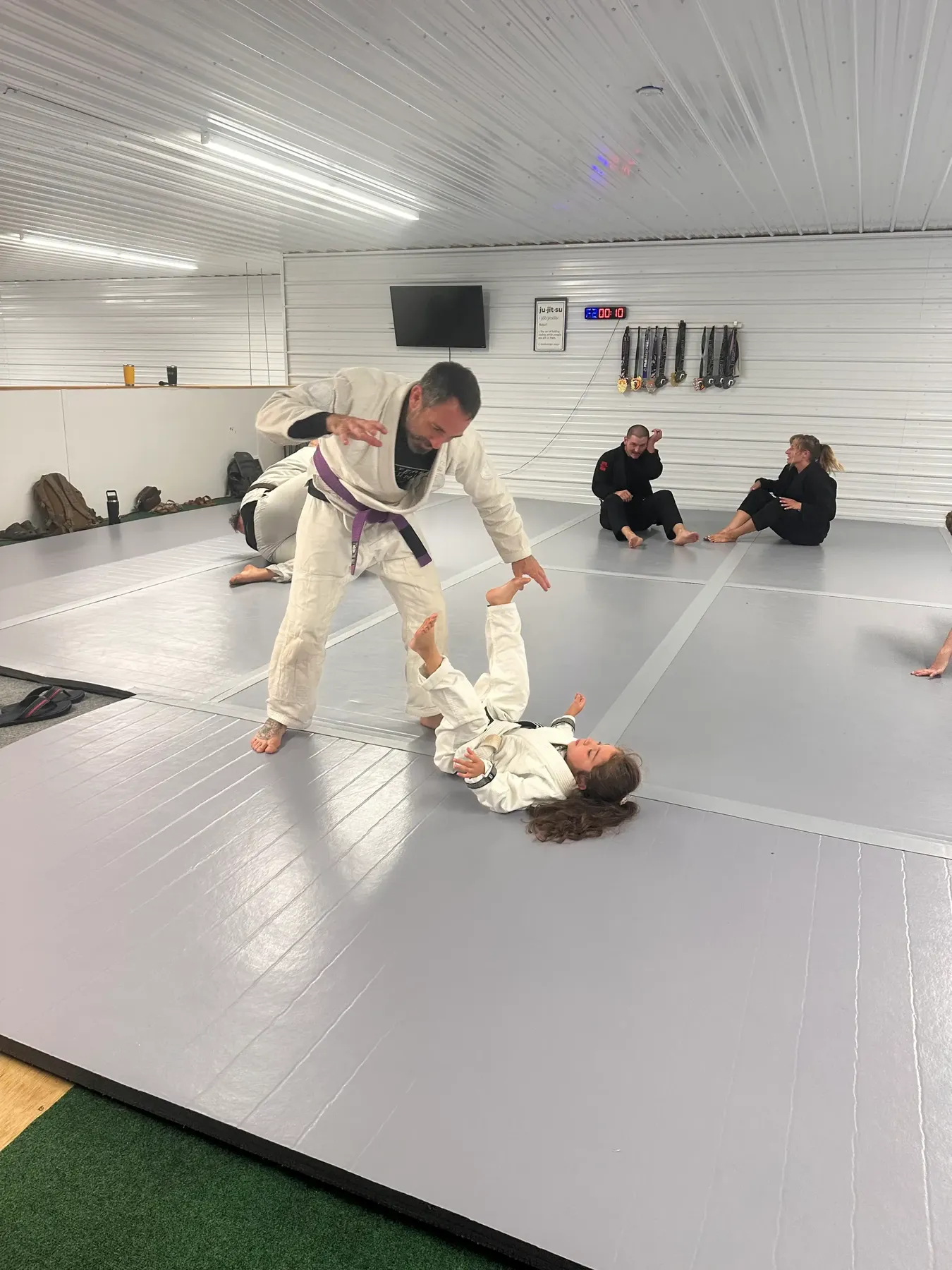 An instructor demonstrates a foundational guard position with a young student.
